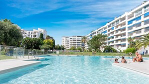 Una piscina con acqua cristallina, circondata da edifici moderni e vegetazione.