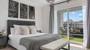 Una camera da letto con un letto, comodini, una panca e vista su un balcone con mobili da esterno.