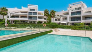 Ein modernes Gebäude mit Swimmingpool, Palmen und blauem Himmel.