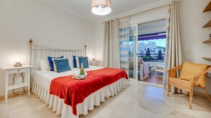 A hotel room with a bed, a nightstand, a chair, and a balcony with a view. - Urban Exclusivity At Puerto Ban s (Marbella)