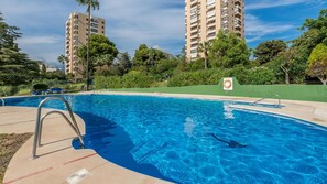 A swimming pool with a lifebuoy sign, surrounded by greenery and tall buildings. - Charming Golfers Place Puerto Banus (Marbella)