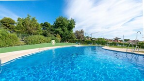 A clear blue swimming pool with a green deck, surrounded by trees and a clear sky. - Charming Golfers Place Puerto Banus (Marbella)