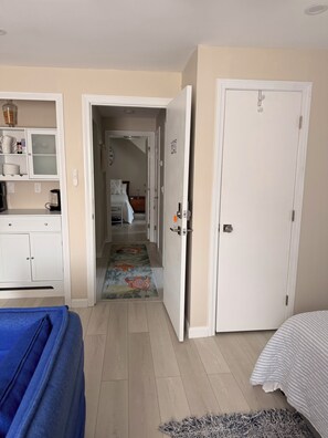Habitación de hotel con cama, escritorio con silla, armario y baño visible a través de una puerta abierta.