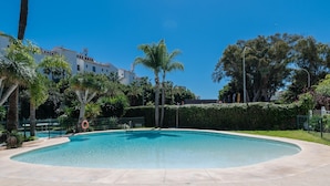 A swimming pool with a surrounding fence, palm trees, and a building in the background. - Luxury Penthouse Mountain SEA Views Puerto Banus (Marbella)