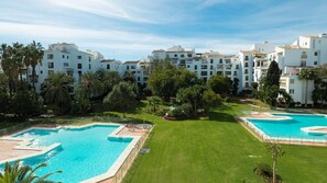 Ein Resort mit mehreren Schwimmbecken, üppigen Grünflächen und weißen Gebäuden.