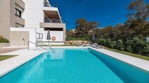 Ein modernes Gebäude mit Swimmingpool, Sitzgelegenheiten im Freien und einem Rettungsring.