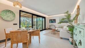 Ein modernes Wohnzimmer mit Essbereich, großen Fenstern und Blick ins Freie.