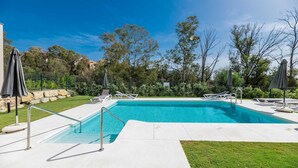 A rectangular swimming pool with a metal safety railing, surrounded by a paved deck. There are lounge chairs and umbrellas around the pool. - Endless Luxury At Marbella Lake Paradise (Marbella)