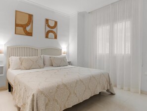 Ein Schlafzimmer mit einem großen Bett, einem Nachttisch und zwei an der Wand befestigten abstrakten Kunstwerken.