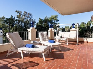 Eine Terrasse mit zwei Liegestühlen, einem kleinen Tisch und einer blauen Dekorationsvase.