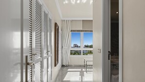 A hallway with a view to a balcony, a door with a handle, and a window with curtains. - Vista mar y Piscina en Puerto Ban s (Marbella)