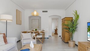 A modern living room with a sofa, coffee table, and a dining area with a table set for two. - Apartamento de 2 Dormitorios con Terraza ref 211 (Marbella)