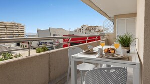 Ein Balkon mit einem Tisch für zwei Personen, einem Blumentopf und Blick auf Gebäude im Hintergrund.