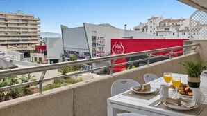 Ein Balkon mit Frühstückstisch, Blick auf eine Stadtlandschaft mit Gebäuden und blauem Himmel.