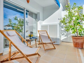 A balcony with two wooden lounge chairs, a small table with a book and a glass of orange juice, and a potted plant. - Precioso Tico con Vistas al mar ref 771 (Marbella)