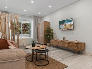 Ein modernes Wohnzimmer mit einer Couch, einem Couchtisch, einem an der Wand befestigten Fernseher und einem Holzschrank.