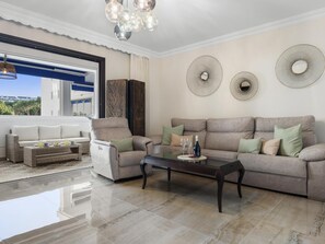 Ein modernes Wohnzimmer mit einer Couch, einem Couchtisch und Blick ins Freie.