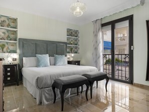 Ein Hotelzimmer mit einem großen Bett, zwei Nachttischen, einer Chandelierleuchtre und einem Balkon mit Aussicht.