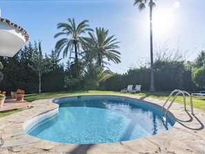 A swimming pool with a stone deck, surrounded by palm trees and a clear sky. - Villa Byrons in Marbella (Marbella)