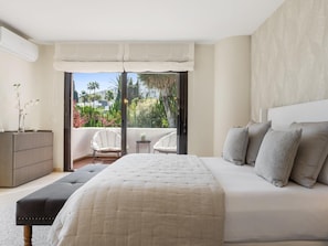 A bedroom with a large bed, a bedside table, a chair, and a view of the outdoors. - Villa Byrons in Marbella (Marbella)