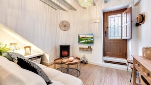 Een gezellige woonkamer met een open haard, een televisie en een houten deur.