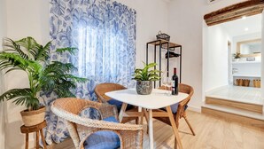 Een eetruimte met rieten stoelen, een witte tafel en een plant in pot.