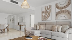 A modern living room with a sectional sofa, a coffee table, and decorative wall art. - Beach Puerto Ban s 3 Br Apartment (Marbella)