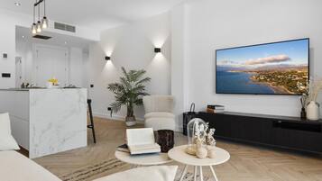 Una sala moderna con un televisor de pantalla plana grande, una isla de cocina de mármol, un sofá cómodo y una planta en maceta.