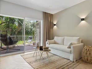 Ein modernes Wohnzimmer mit einer Couch, einem Couchtisch und Blick auf einen Balkon mit Gartenmöbeln.