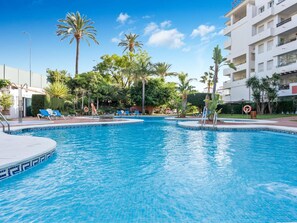 Ein Swimmingpool mit Liegestühlen und Palmen.