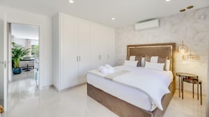 Ein modernes Schlafzimmer mit einem großen Bett, einem weißen Kleiderschrank und einem Blumentopf.