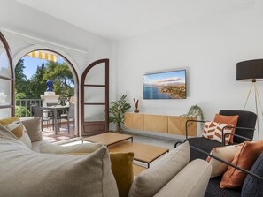 Ein modernes Wohnzimmer mit einer Couch, einem Couchtisch und einem an der Wand befestigten Fernseher.