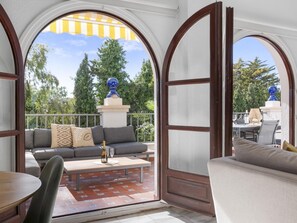 Ein möblierter Patio-Bereich mit einer Couch, einem Tisch und Blick auf die umgebende Natur.