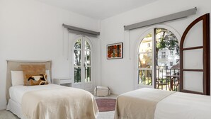 Una habitació d'hotel amb dos llits, una finestra amb vista a l'exterior i una taula petita amb caires.