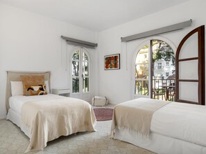 Ein Hotelzimmer mit zwei Betten, einem Fenster mit Blick ins Freie und einem kleinen Tisch mit Stühlen.