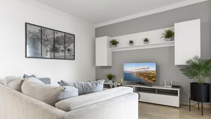 Ein modernes Wohnzimmer mit einem grauen Sofa, einem Flachbildfernseher und einer Weltkarte als Wandbild.