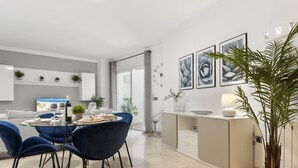 Ein moderner Essbereich mit einem runden Tisch, blauen Stühlen und einer Küche mit weißer Arbeitsplatte und Schränken.