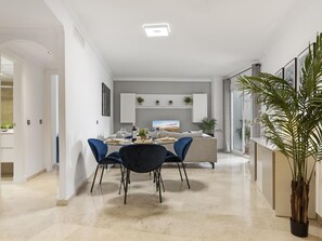 Ein modernes Interieur mit Essbereich, einer Couch und einer großen Pflanze.