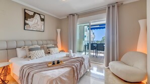 A modern hotel room with a large bed, a seating area, and a balcony with a view. - The Diamond Of Puerto Banus With Seaviews (Marbella)
