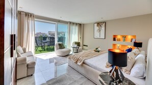 A modern hotel room with a large balcony, a sofa, a bed, and a desk. - The Diamond Of Puerto Banus With Seaviews (Marbella)