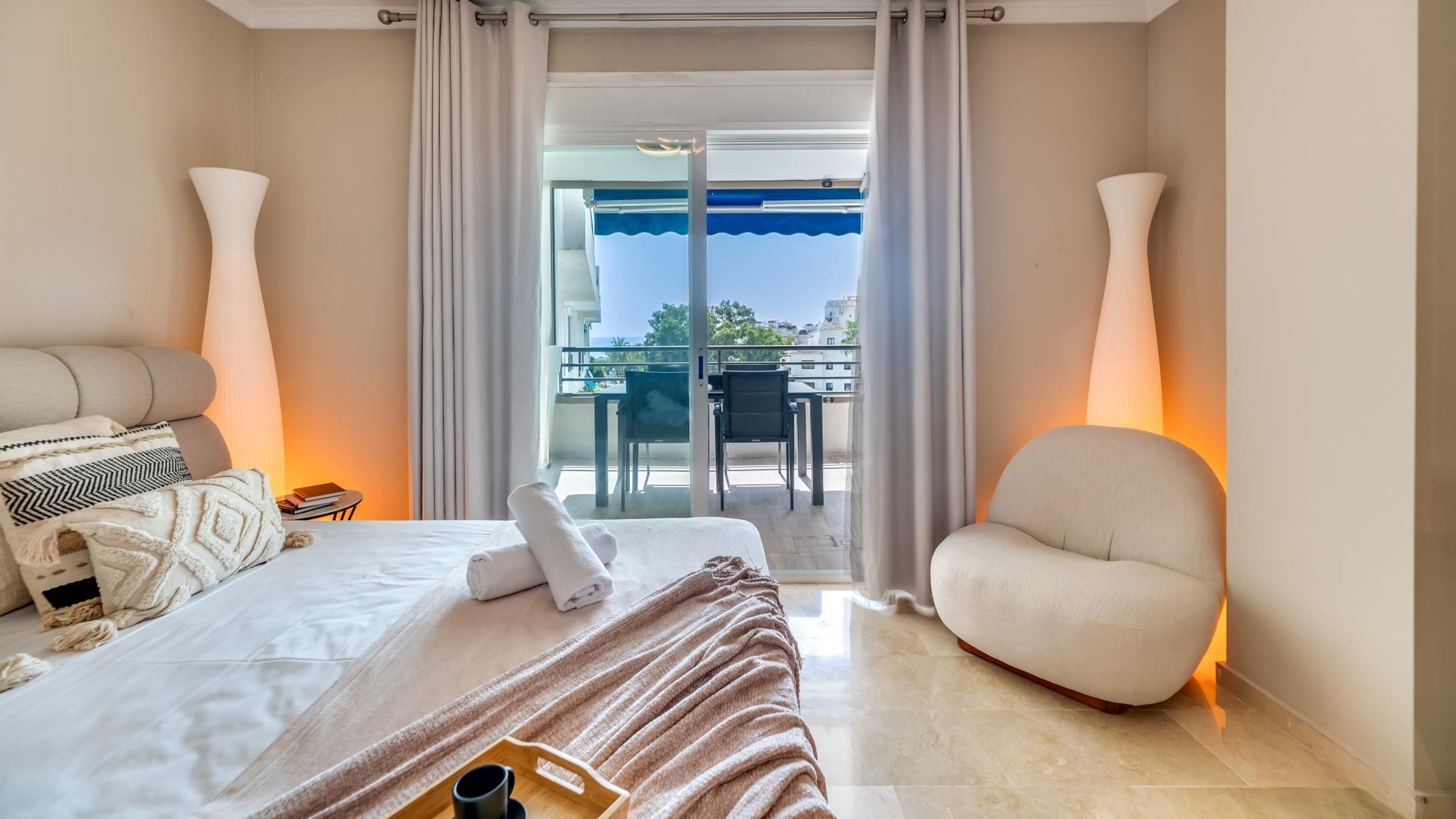 Una habitación de hotel con cama, una silla, una mesa y un balcón con vistas.