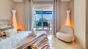 A hotel room with a bed, a chair, a table, and a balcony with a view. - The Diamond Of Puerto Banus With Seaviews (Marbella)