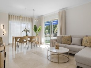 A modern living room with a sofa, a coffee table, and a dining area with chairs and a table. - Terrazas DE Banus 4 12 (Marbella)