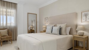 Quarto com uma cama grande, mesas de cabeceira, uma cadeira e um espelho.