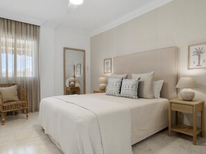 Ein Schlafzimmer mit einem großen Bett, Nachttischen, einem Sessel und einem Spiegel.