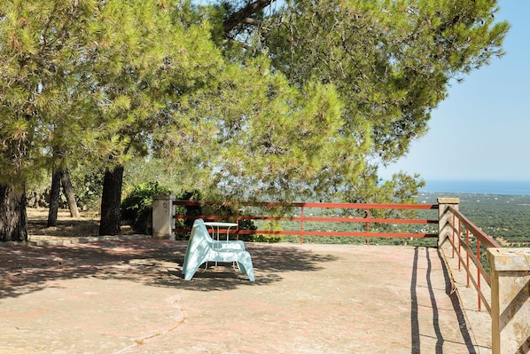 Een terras met tafel en stoelen, omringd door bomen en uitzicht op het landschap.