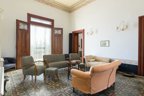 Ein Wohnzimmer mit gemusterten Bodenfliesen, einer Sofagarnitur, einem Sessel und einem Tisch.