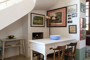 Un coin repas avec une table blanche, un bol bleu et des chaises.