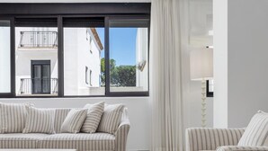 Un soggiorno moderno con un divano a righe, un tavolino e vista su un edificio attraverso ampie finestre.