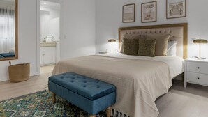 Una camera da letto con un letto grande, comodini, una panca e quadri appesi al muro.